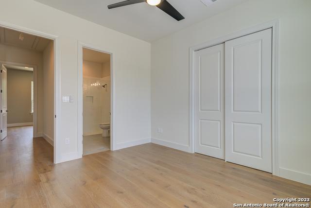 unfurnished bedroom with ensuite bath, light hardwood / wood-style floors, a closet, and ceiling fan