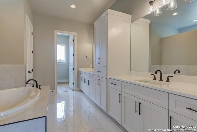 bathroom featuring vanity and tiled bath