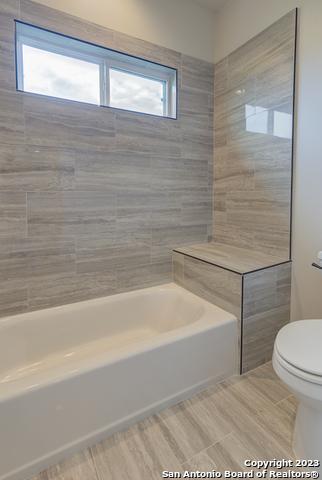 bathroom with tiled shower / bath combo and toilet