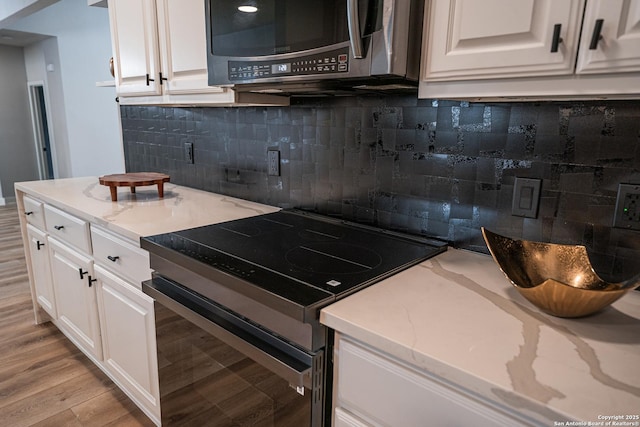 kitchen featuring white cabinetry, light stone counters, light hardwood / wood-style floors, and appliances with stainless steel finishes