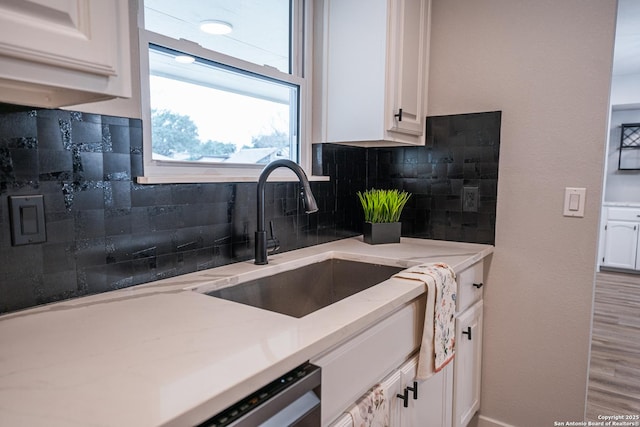 kitchen with light stone counters, sink, and white cabinets