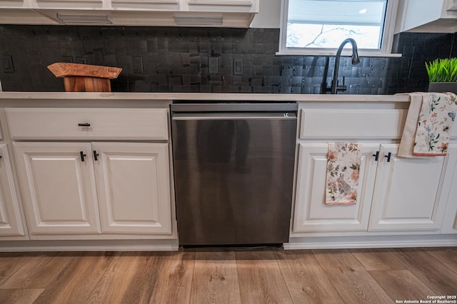 kitchen featuring backsplash, stainless steel dishwasher, light hardwood / wood-style floors, and white cabinets