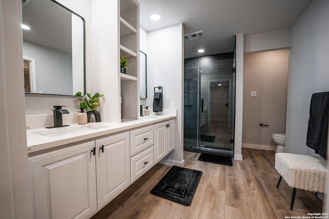 bathroom with wood-type flooring, toilet, a shower with shower door, and vanity