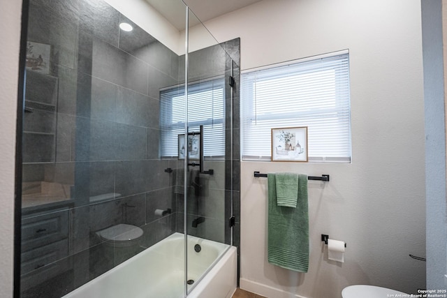 bathroom with bath / shower combo with glass door and toilet