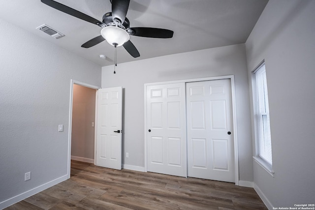 unfurnished bedroom featuring ceiling fan, dark hardwood / wood-style flooring, and a closet