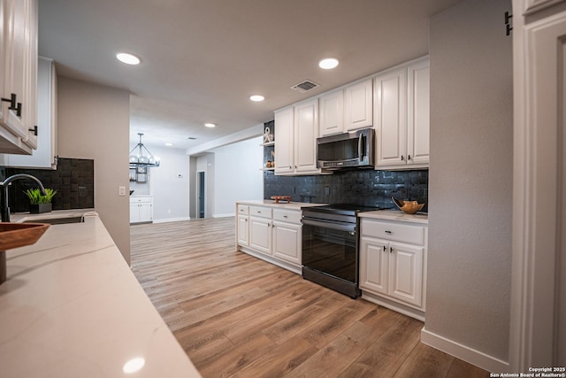 kitchen featuring range with electric cooktop, pendant lighting, sink, white cabinets, and light wood-type flooring