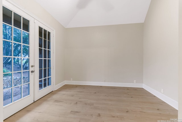 spare room with light hardwood / wood-style flooring, french doors, and vaulted ceiling