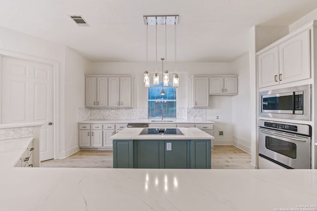 kitchen with pendant lighting, sink, appliances with stainless steel finishes, white cabinets, and a kitchen island