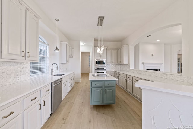 kitchen with sink, decorative light fixtures, a kitchen island, stainless steel appliances, and white cabinets