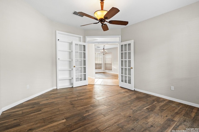 spare room with dark hardwood / wood-style floors, ceiling fan with notable chandelier, and french doors