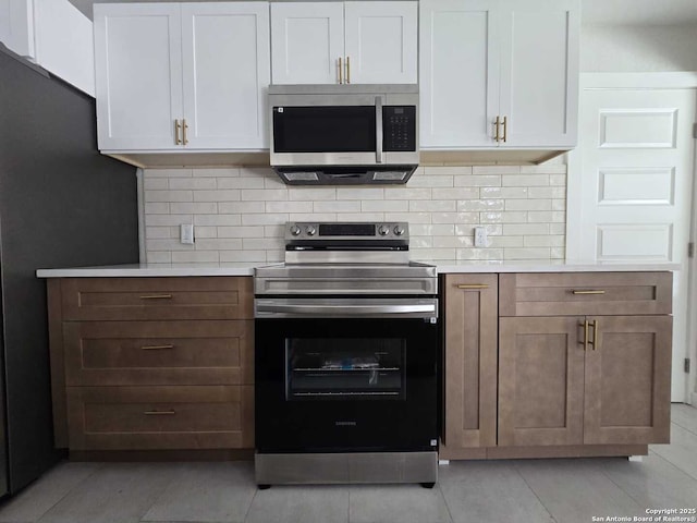 kitchen featuring white cabinetry, appliances with stainless steel finishes, light tile patterned floors, and backsplash