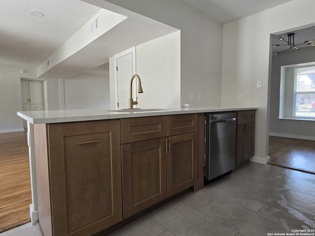 kitchen with dishwasher, dark brown cabinets, sink, and kitchen peninsula