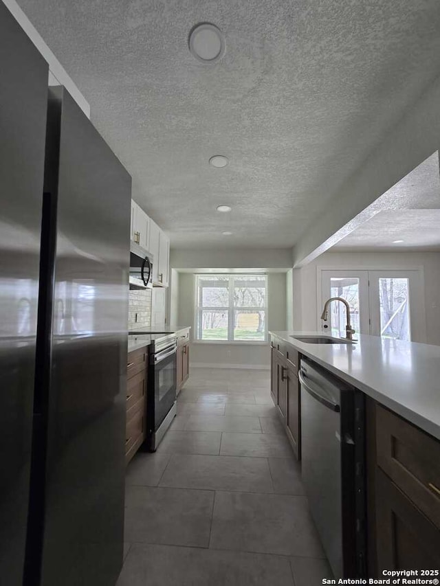 kitchen with sink, white cabinetry, a textured ceiling, appliances with stainless steel finishes, and backsplash