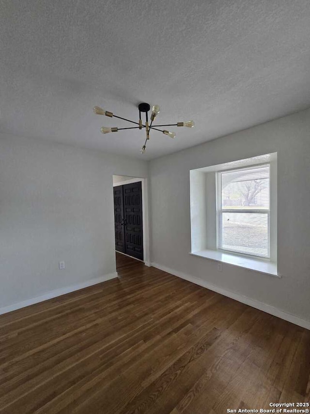 unfurnished room featuring dark wood-type flooring and a textured ceiling