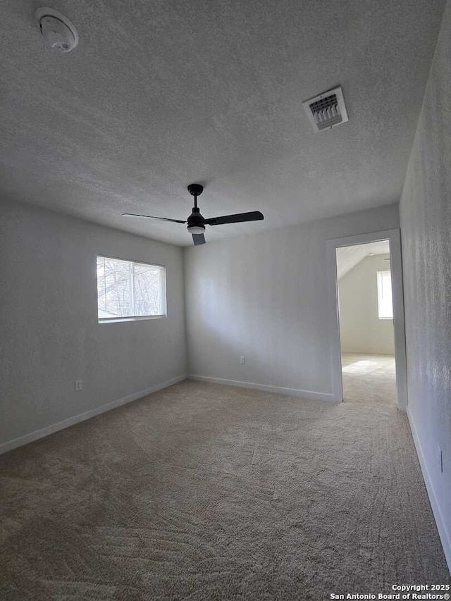 carpeted empty room featuring ceiling fan and a textured ceiling