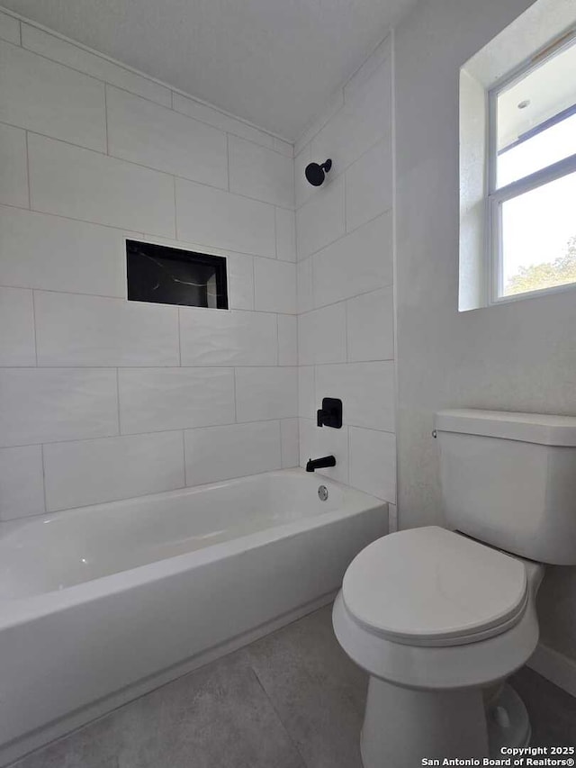 bathroom featuring tile patterned flooring, tiled shower / bath, and toilet