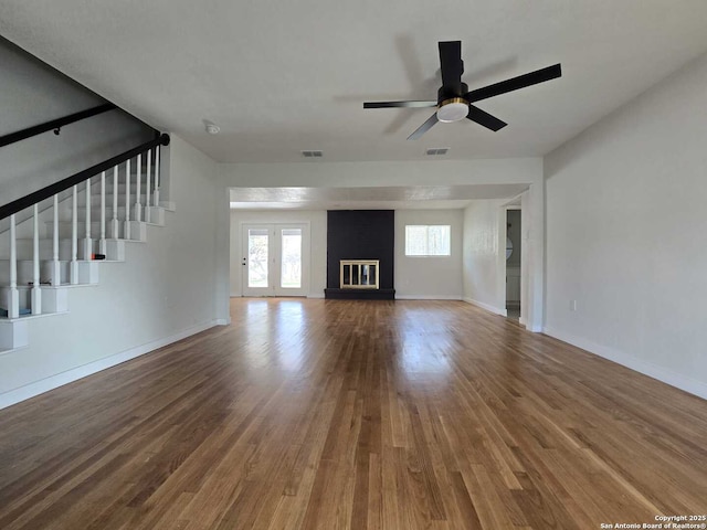 unfurnished living room featuring ceiling fan, a large fireplace, and hardwood / wood-style floors