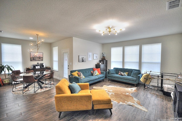 living room featuring a notable chandelier, dark hardwood / wood-style floors, and a textured ceiling