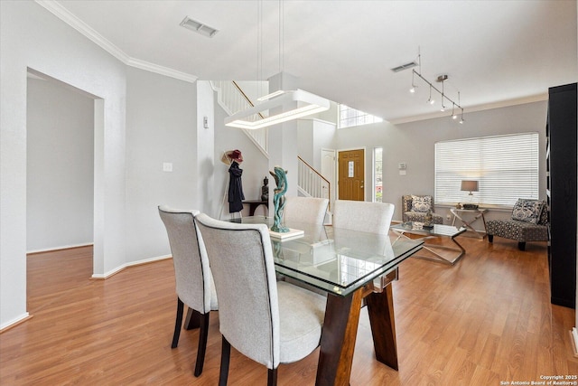 dining space with ornamental molding and light wood-type flooring