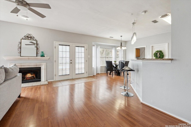 living room featuring ceiling fan with notable chandelier, light hardwood / wood-style floors, and french doors