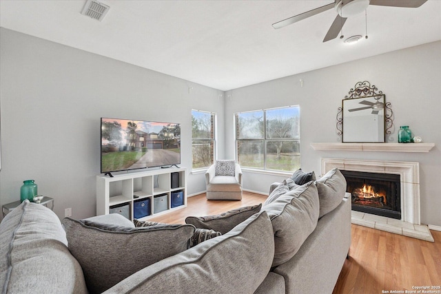 living room with hardwood / wood-style flooring, ceiling fan, and a fireplace