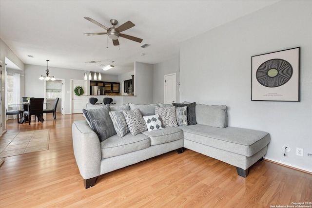 living room with hardwood / wood-style floors and ceiling fan with notable chandelier