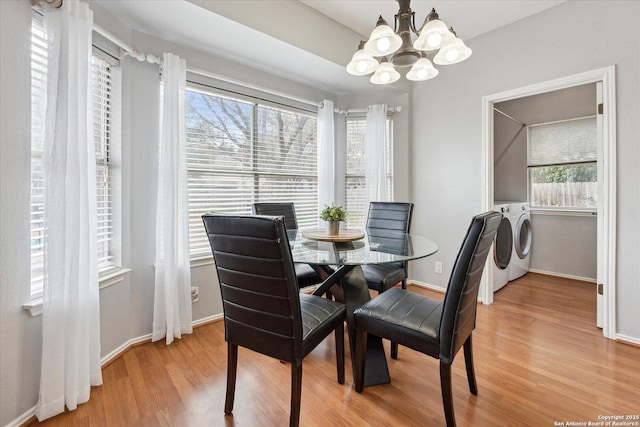 dining room with light hardwood / wood-style floors, washer and dryer, and a chandelier