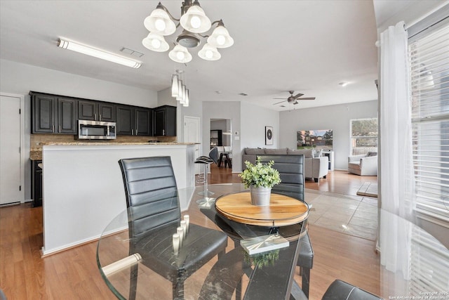 dining space featuring ceiling fan with notable chandelier and light wood-type flooring