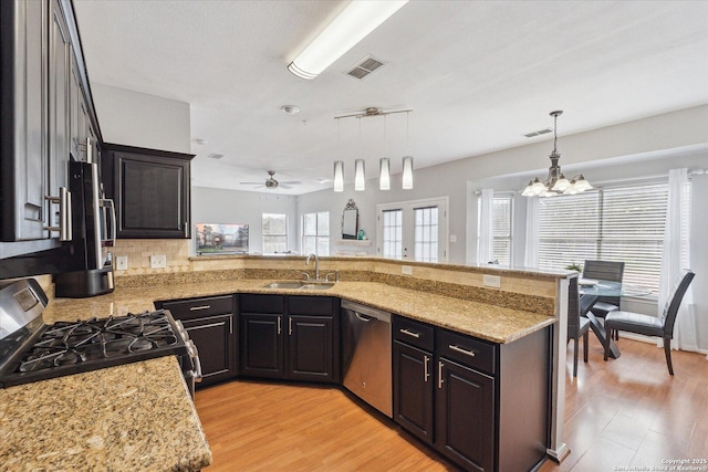 kitchen with hanging light fixtures, stainless steel appliances, sink, and light stone countertops