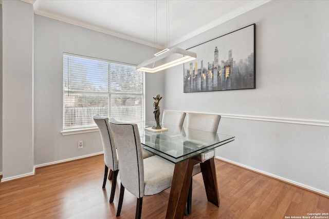 dining space with wood-type flooring and ornamental molding