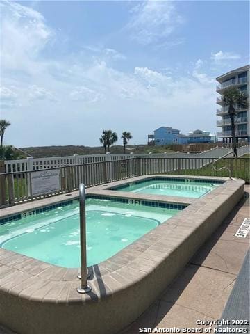 view of swimming pool with a hot tub