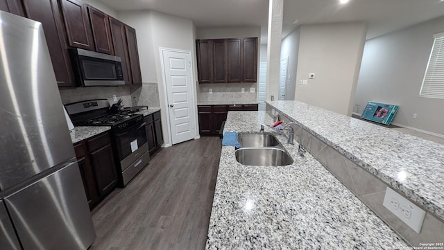 kitchen with tasteful backsplash, appliances with stainless steel finishes, sink, and light stone counters