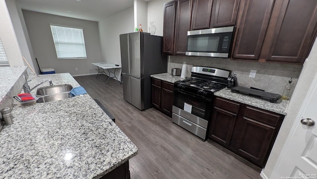 kitchen featuring light stone countertops, appliances with stainless steel finishes, light wood-type flooring, and decorative backsplash