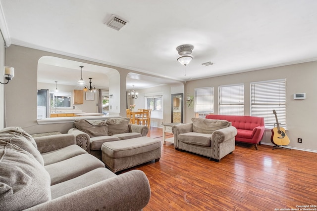 living room with an inviting chandelier, ornamental molding, and wood-type flooring