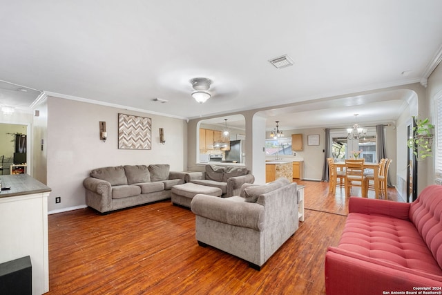 living room with an inviting chandelier, ornamental molding, and wood-type flooring