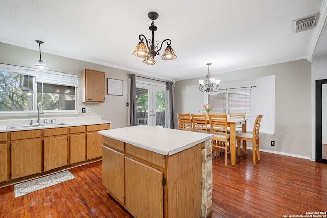 kitchen with dark hardwood / wood-style floors, pendant lighting, sink, a center island, and a notable chandelier