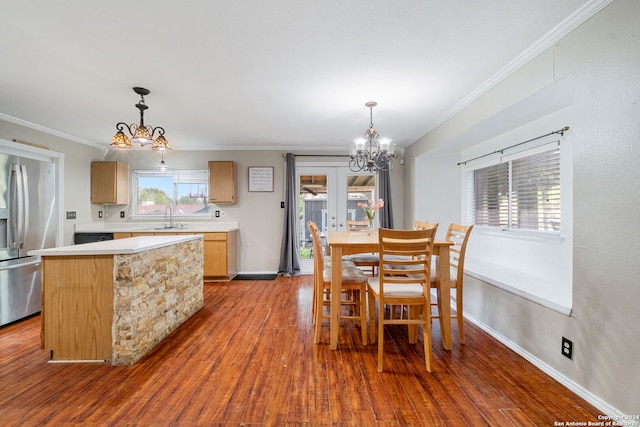 dining space featuring hardwood / wood-style flooring, ornamental molding, sink, and a notable chandelier