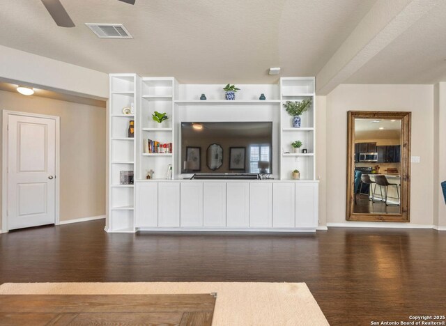 unfurnished living room featuring dark wood-type flooring and ceiling fan