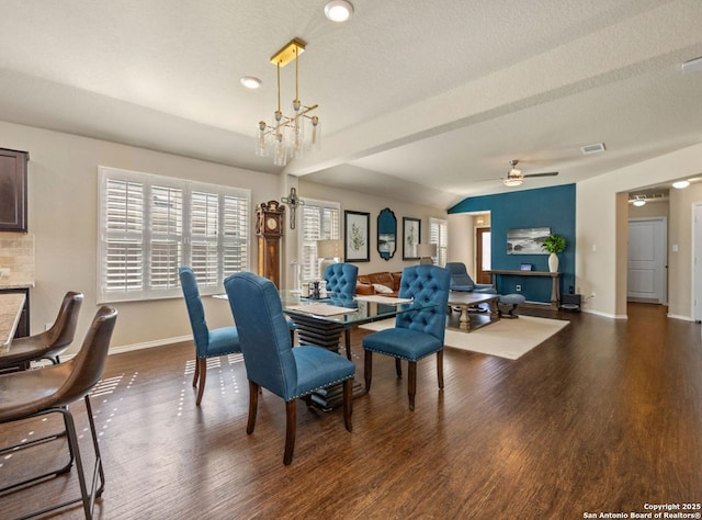 dining space with ceiling fan with notable chandelier, dark hardwood / wood-style floors, and a textured ceiling