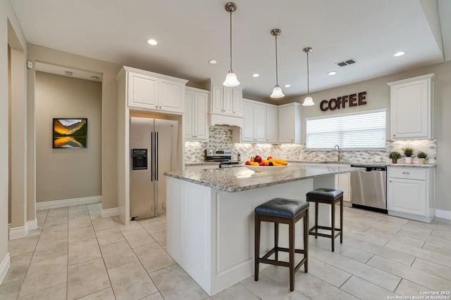 kitchen featuring sink, white cabinetry, light stone counters, a center island, and stainless steel appliances