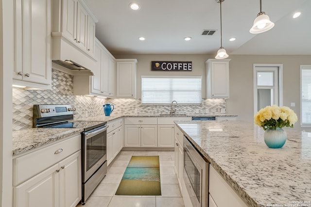 kitchen featuring stainless steel appliances, light stone countertops, white cabinets, and decorative light fixtures