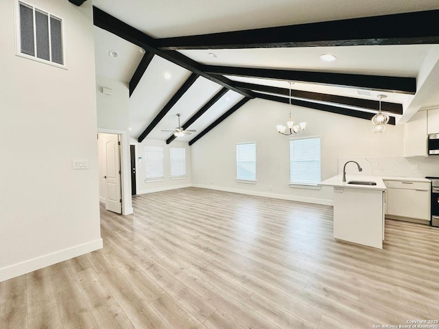 unfurnished living room featuring beamed ceiling, sink, ceiling fan with notable chandelier, and light hardwood / wood-style floors