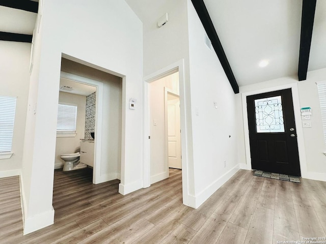 foyer entrance with beamed ceiling, high vaulted ceiling, a wealth of natural light, and light wood-type flooring