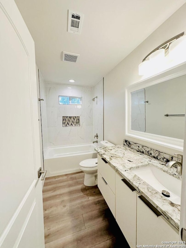 full bathroom featuring vanity, tiled shower / bath, hardwood / wood-style floors, and toilet