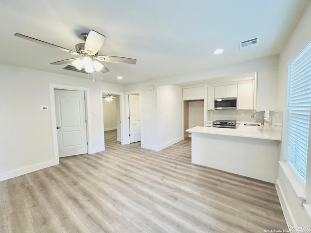 kitchen featuring sink, white cabinets, kitchen peninsula, stainless steel appliances, and light hardwood / wood-style flooring