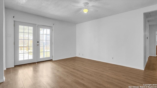 unfurnished room with french doors, a healthy amount of sunlight, hardwood / wood-style floors, and a textured ceiling