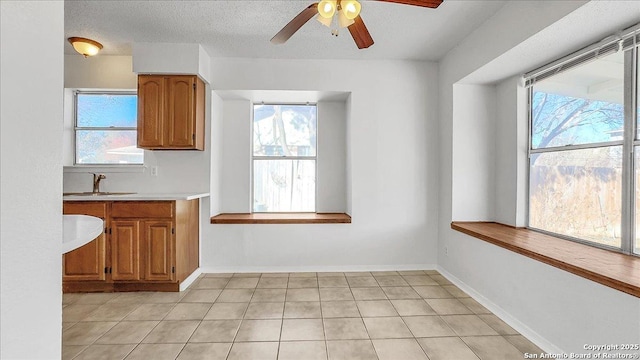 kitchen featuring light tile patterned flooring, sink, a textured ceiling, and a wealth of natural light