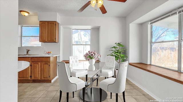 dining space featuring light tile patterned flooring, a healthy amount of sunlight, sink, and a textured ceiling