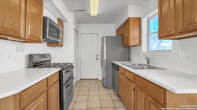 kitchen with sink, light tile patterned floors, a textured ceiling, and appliances with stainless steel finishes