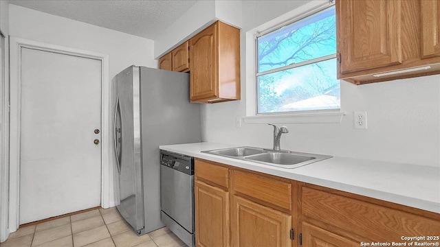 kitchen featuring dishwasher, sink, a textured ceiling, and light tile patterned floors